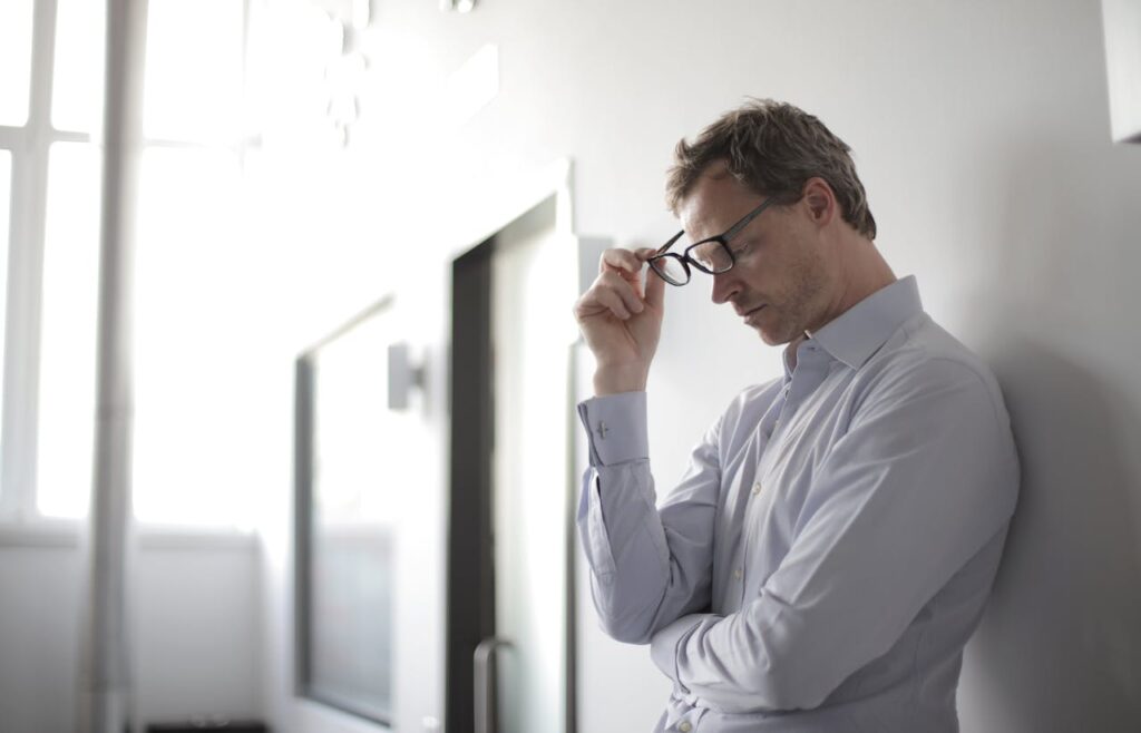 Man taking off his glasses in deep train of thought