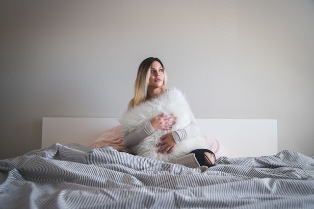 Woman in bed holding a pillow preparing for sleep