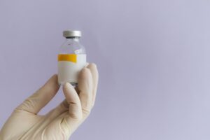 A lab technician's hand holding a PEGylated peptide vial.