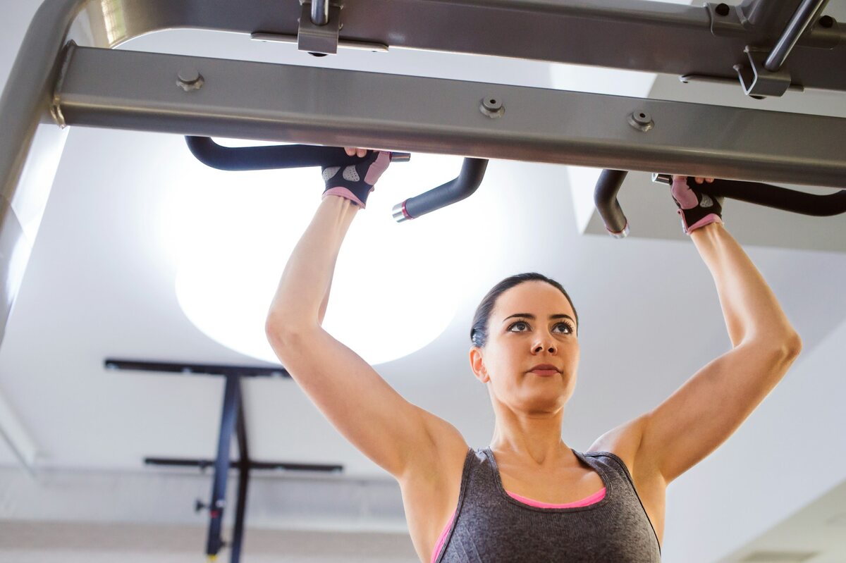 A woman doing pull-ups in the gym.