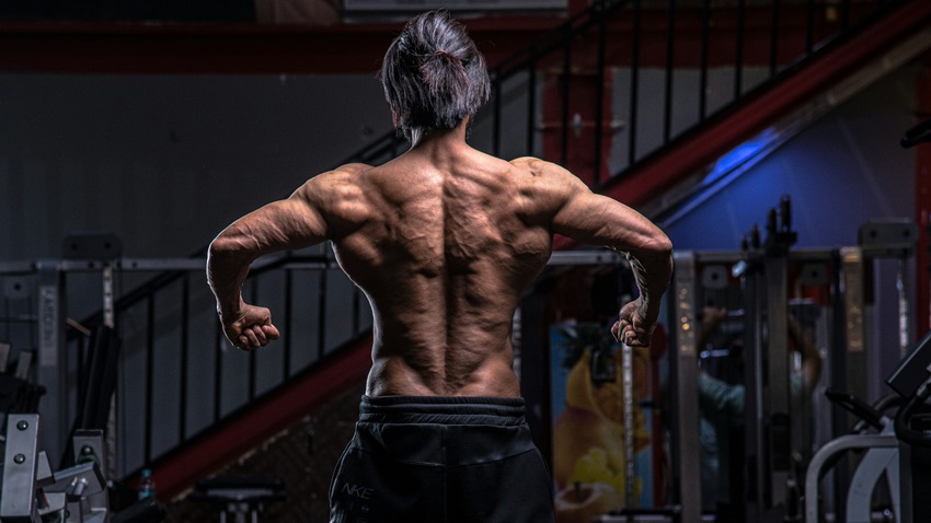 Bodybuilder flexing his back muscles in the gym.